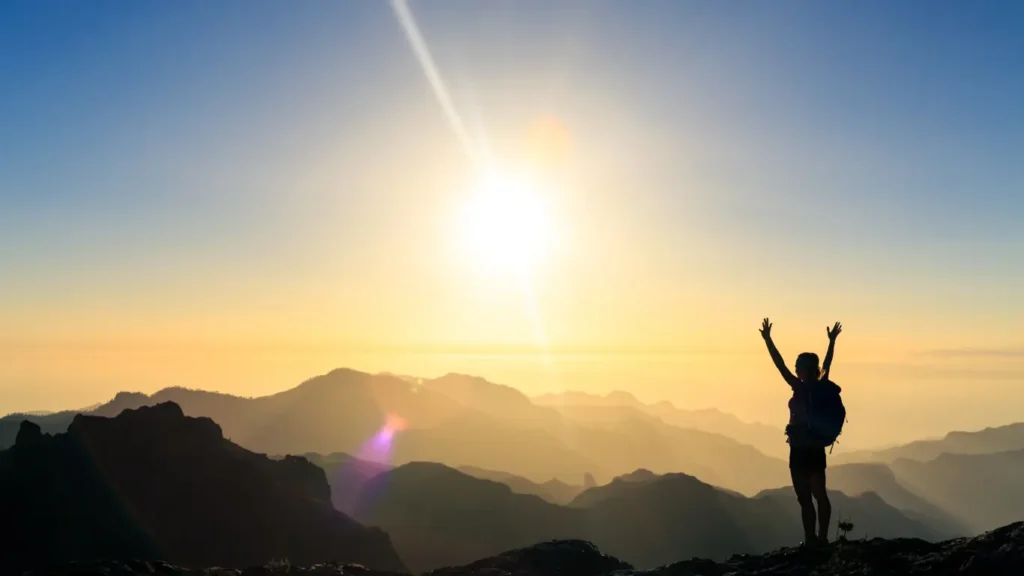 réussir montrer les bénéfices : femme face au soleil au sommet d'une montagne